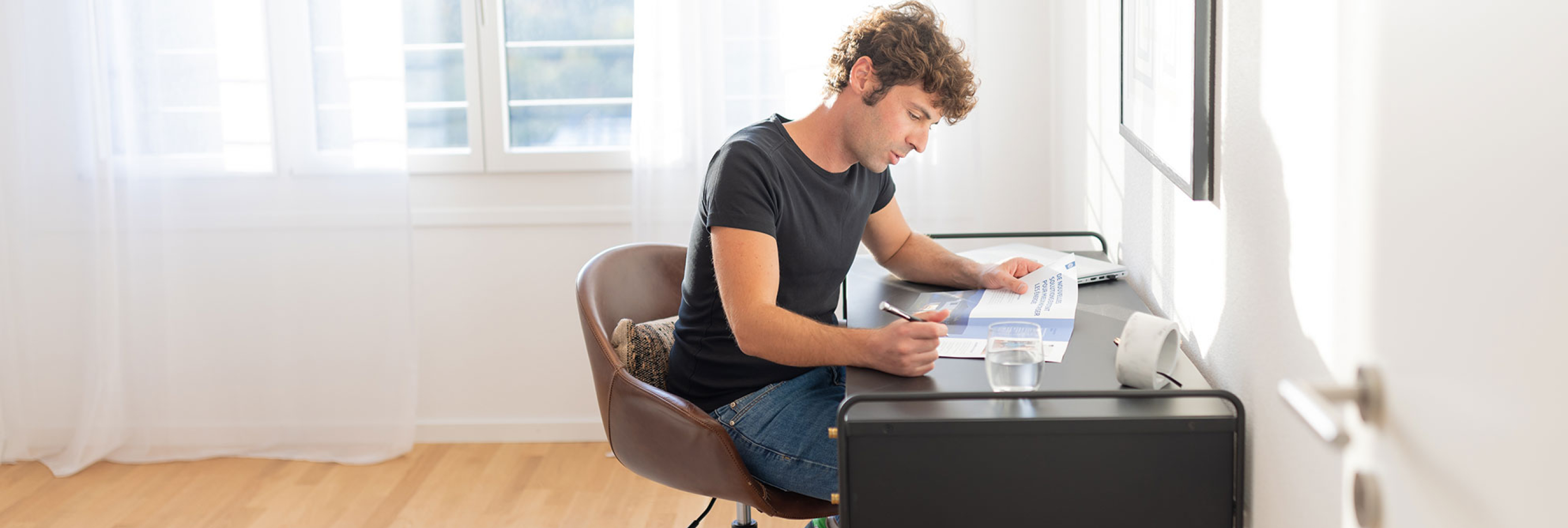homme en train de lire avec verre d'eau adoucie dans habitat confortable.