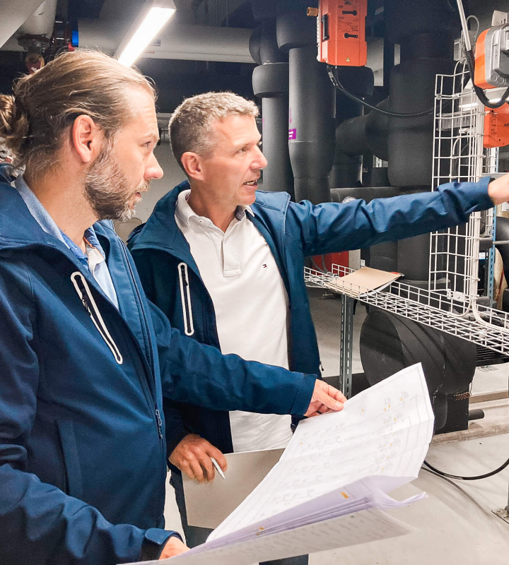 Deux collaborateurs de Groupe E analysent une installation de chauffage