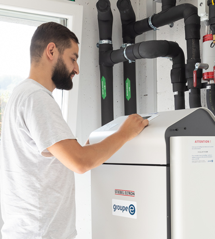un collaborateur de Groupe E effectue la maintenance d'une pompe à chaleur