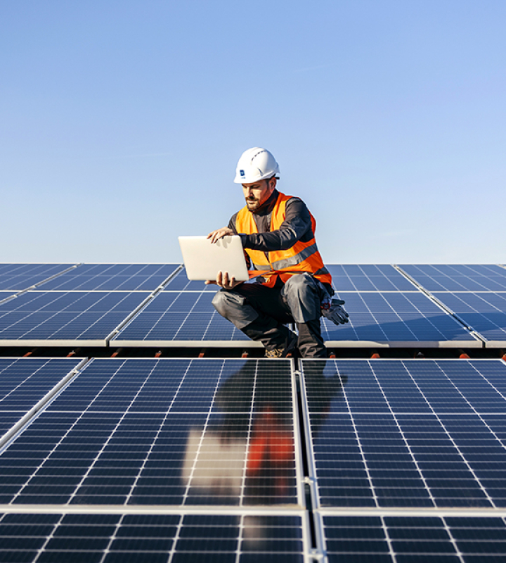 Un technicien effectue de la maintenance de panneaux solaires sur un toit. 
