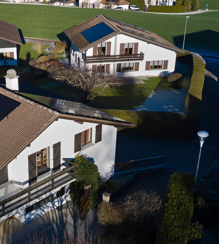 Vue aérienne d'un quartier, dont les maisons sont équipées de panneaux solaires installés par Groupe E