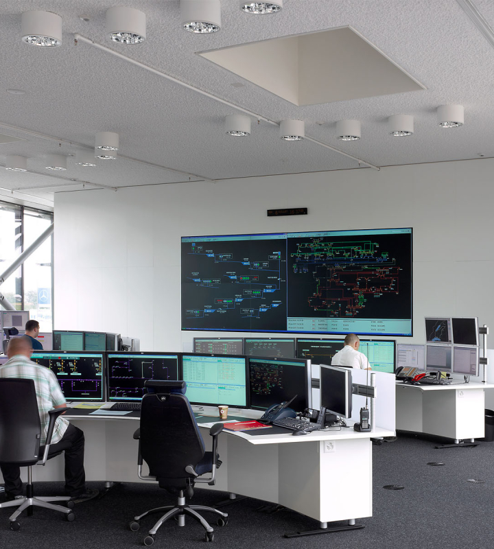Salle de contrôle avec des écrans et des opérateurs travaillant, illustrant les solutions d'automation et de contrôle-commande proposées par Groupe E pour les professionnels
