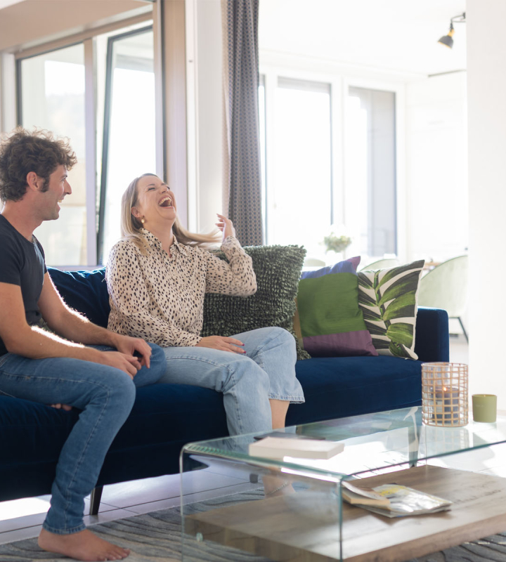 Un couple installée sur son canapé, dans une maison équipée de domotique Groupe E