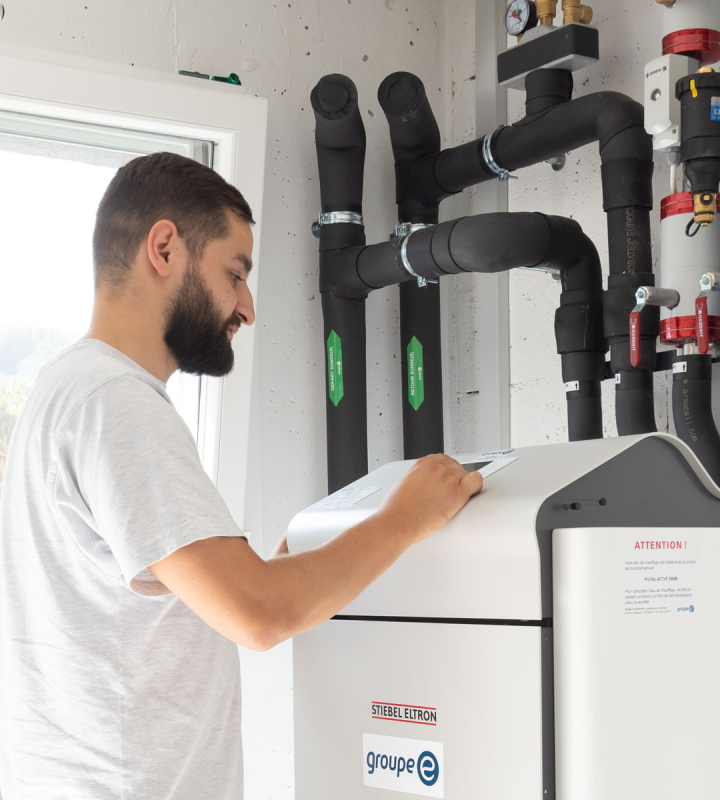 Ein Mitarbeiter von Groupe E führt die Wartung einer Wärmepumpe durch