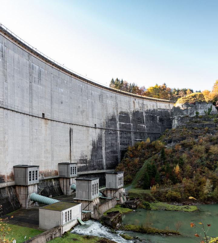 Vue d’un barrage hydroélectrique entouré de nature automnale, illustrant l’expertise de Groupe E dans le domaine de l’hydroélectricité et ses formations spécialisées
