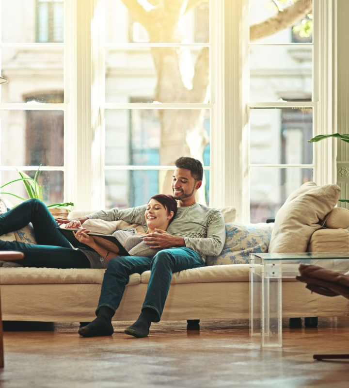 Un couple profite d’un moment de détente dans un salon lumineux et chaleureux, symbolisant le confort offert par le gaz naturel, une solution énergétique proposée par Groupe E pour les particuliers