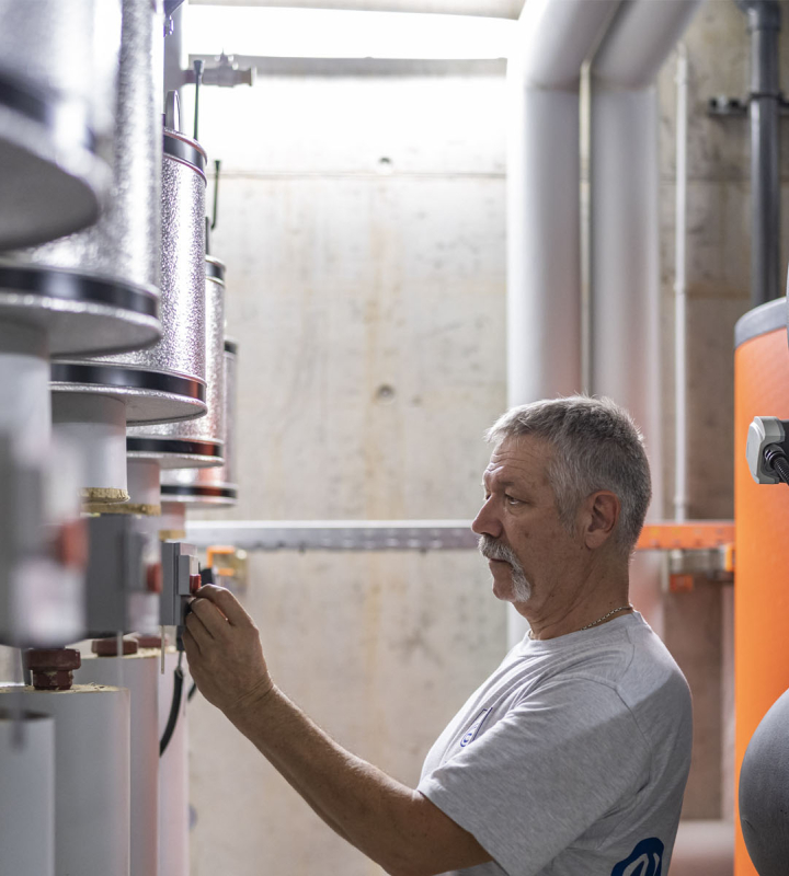 Un collaborateur de Groupe E effectue la maintenance d'une installation CVCS 