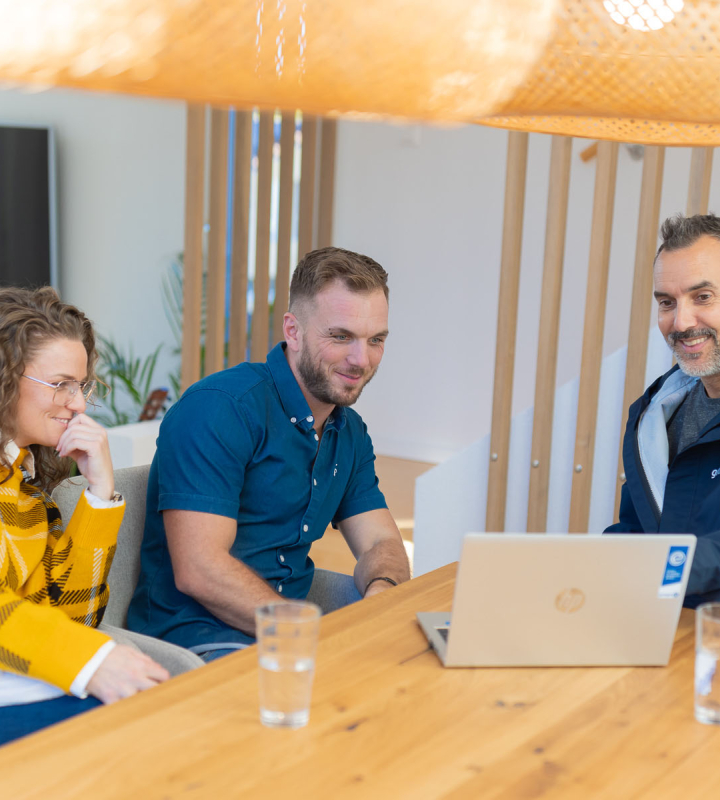 Ein Mitarbeiter der Groupe E diskutiert mit Kunden an einem Tisch über geeignete Energielösungen.