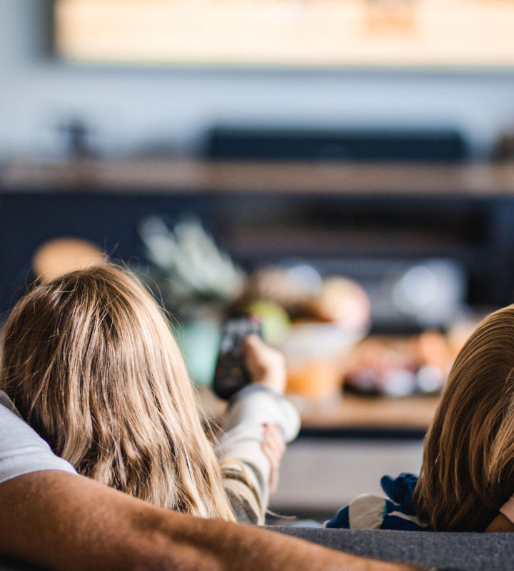 famille confortablement installée dans son salon, symbolisant la fiabilité du raccordement au réseau électrique assuré par Groupe E