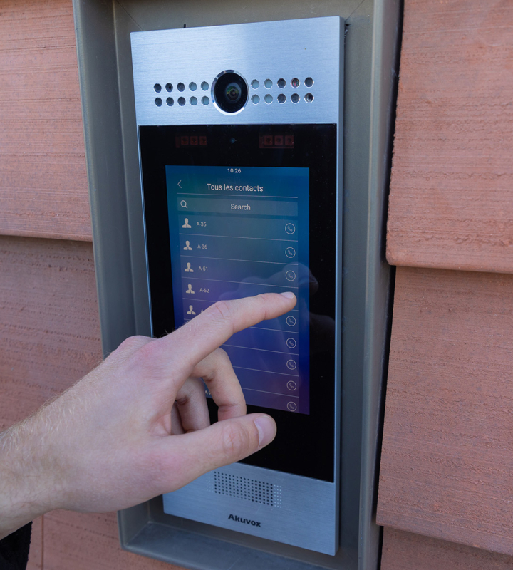 Eine Hand sucht nach einer Person auf einer digitalen Türklingel