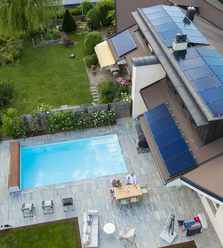 Vue aérienne d'une maison équipée de panneaux solaires, symbolisant l'engagement durable de Groupe E pour son produit électricité Vario destiné aux clients privés