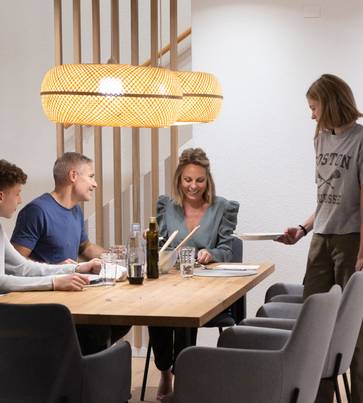 Une famille partage un repas dans une maison chauffée grâce à une solution de Groupe E