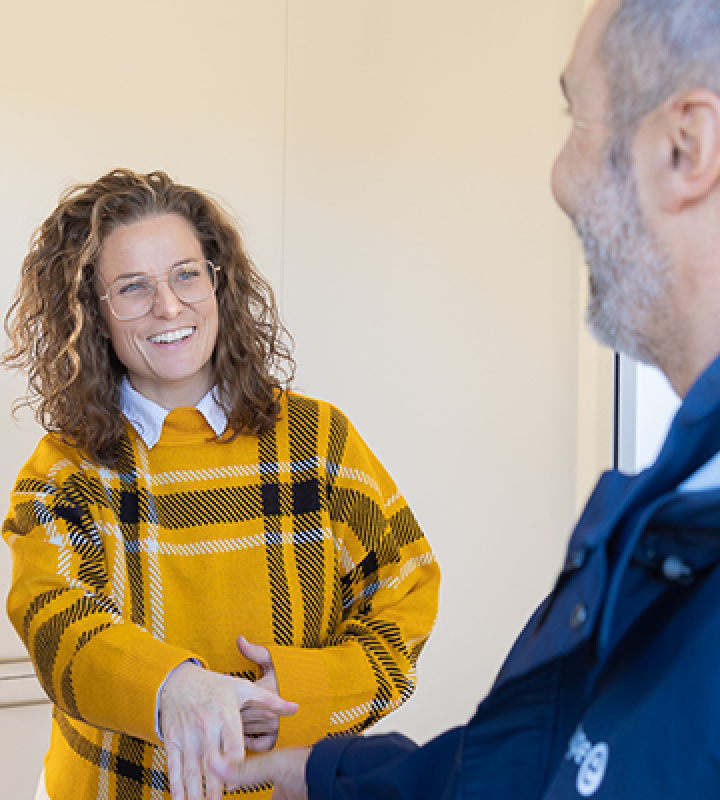 Ein Mitarbeiter von Groupe E vor der Haustür eines Kundenpaares. 