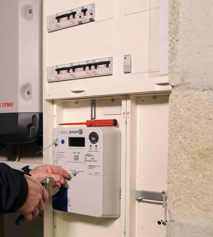 Un technicien de Groupe E installe un compteur intelligent chez un client