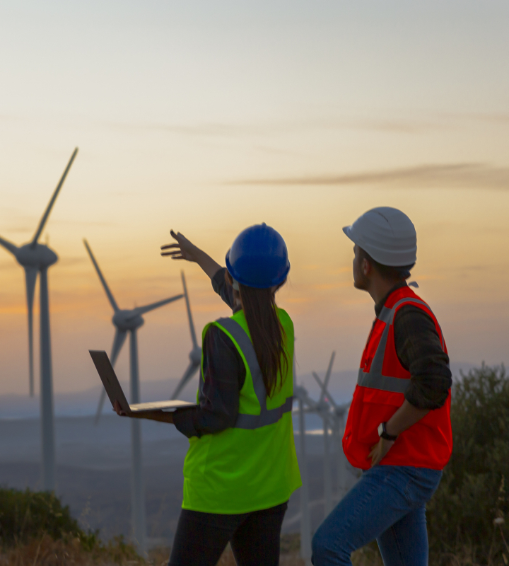 Photo d'un paysage avec des éoliennes et deux personnes analysant les possibilité d'en construire de nouvelle