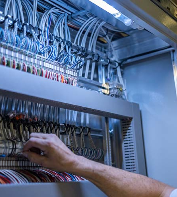 Un collaborateur de Groupe E effectue de la maintenance dans un tableau électrique