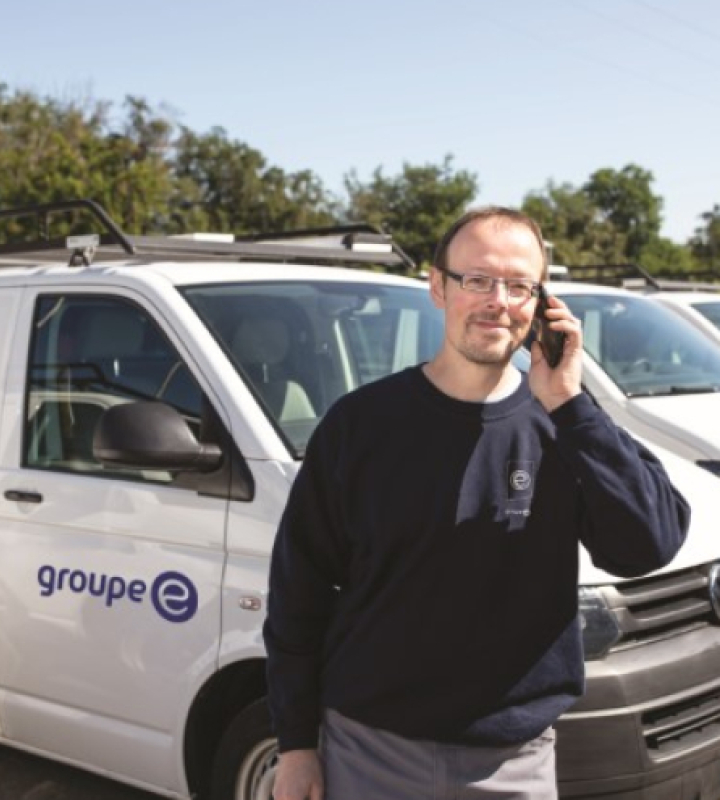 Un technicien au téléphone devant une camionnette Groupe E