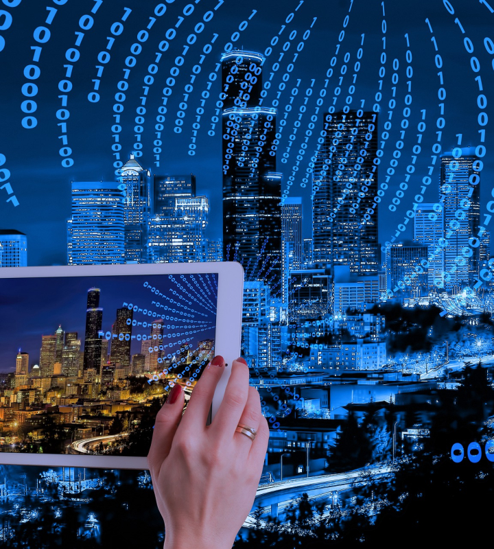 Eine Person hält ein Tablet, das eine bei Nacht beleuchtete Stadt zeigt, umgeben von einem Datenstrom aus Nullen und Einsen. Das Bild veranschaulicht das Konzept einer intelligenten und vernetzten Stadt und symbolisiert den Einsatz von Technologie und Daten zur Verwaltung urbaner Infrastrukturen – ein Bereich, in dem Groupe E mit intelligenten Energielösungen tätig werden könnte.