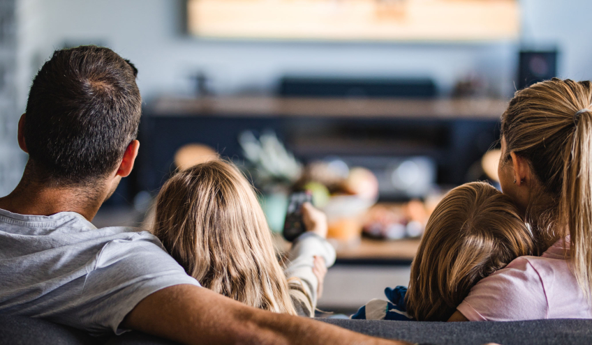 Familie gemütlich im Wohnzimmer, als Symbol für die Zuverlässigkeit des Stromnetzanschlusses von Groupe E