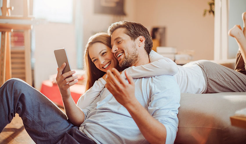 couple heureux qui consulte sa facture d'électricité Groupe E