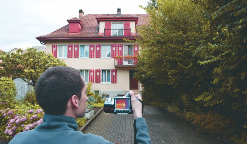 Techniker der Groupe E, der die Thermografie eines Gebäudes durchführt