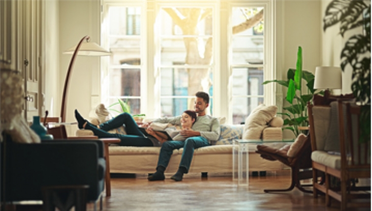 Couple installé sur un canapé, dans un appartement confortable