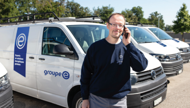 Un technicien Groupe E au téléphone devant des camionettes