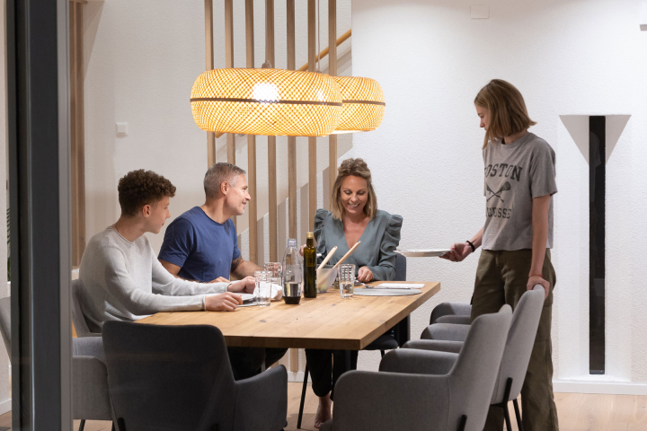 Une famille partage un repas dans une maison chauffée grâce à une solution de Groupe E