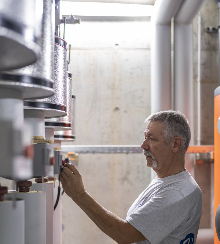 Un collaborateur de Groupe E effectue la maintenance d'une installation CVCS 