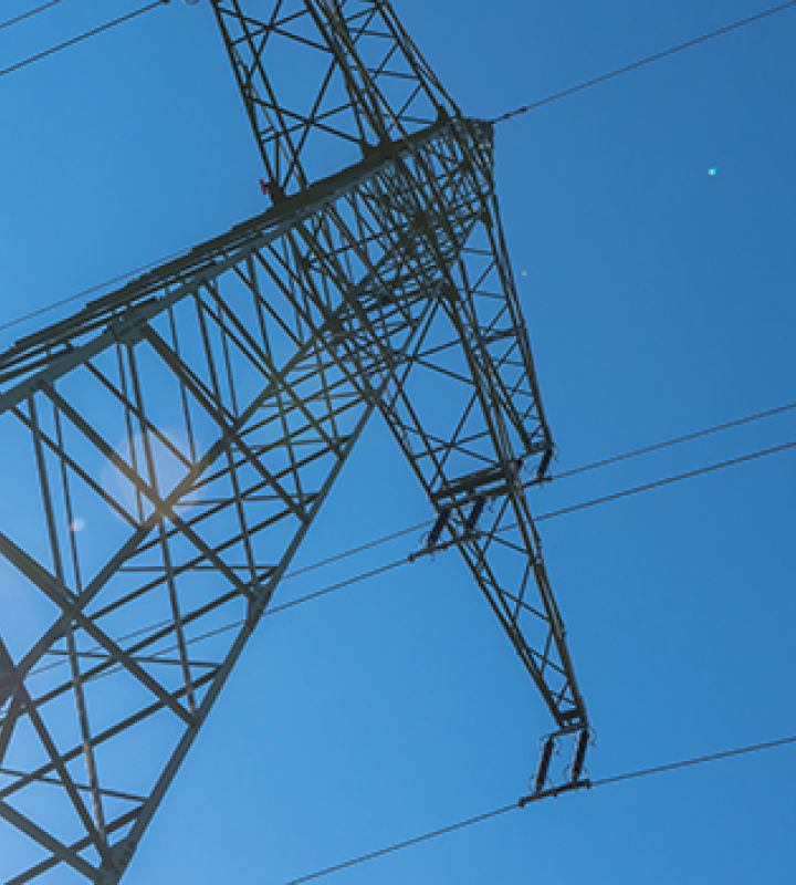 Hochspannungsmast unter blauem Himmel mit Sonnenlicht, Energieinfrastruktur von Groupe E.