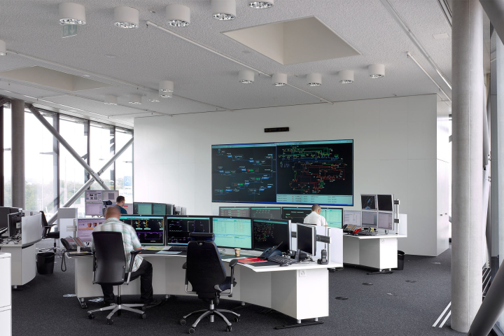 Salle de contrôle avec des écrans et des opérateurs travaillant, illustrant les solutions d'automation et de contrôle-commande proposées par Groupe E pour les professionnels