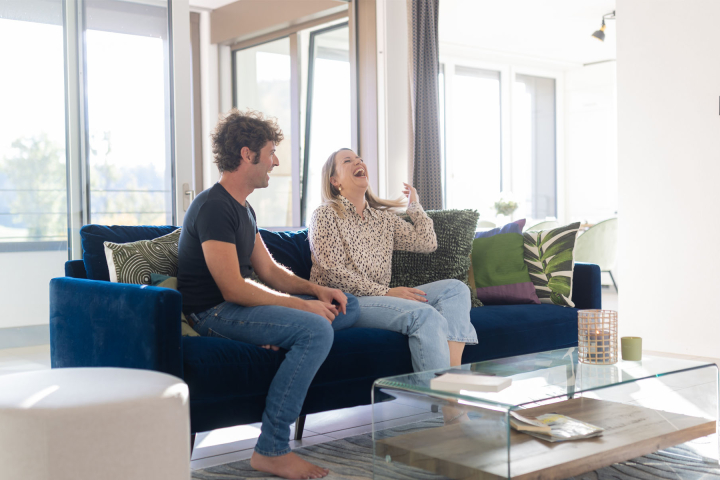 Un couple installée sur son canapé, dans une maison équipée de domotique Groupe E