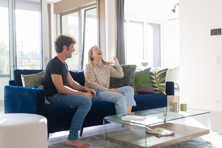 Un couple installée sur son canapé, dans une maison équipée de domotique Groupe E
