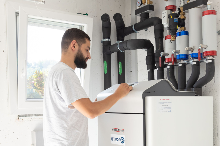 un collaborateur de Groupe E effectue la maintenance d'une pompe à chaleur
