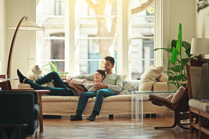 Un couple profite d’un moment de détente dans un salon lumineux et chaleureux, symbolisant le confort offert par le gaz naturel, une solution énergétique proposée par Groupe E pour les particuliers