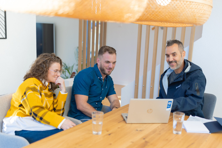 Un collaborateur de Groupe E échange avec des clients autour d’une table pour discuter de solutions énergétiques adaptées.