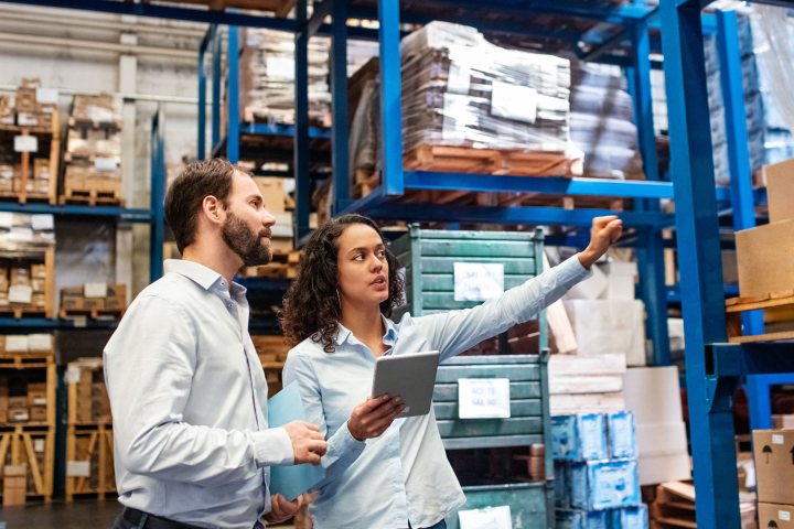 Discussion entre deux collaborateurs dans l’entrepôt d’une grande entreprise, centrée sur l’optimisation des processus industriels.