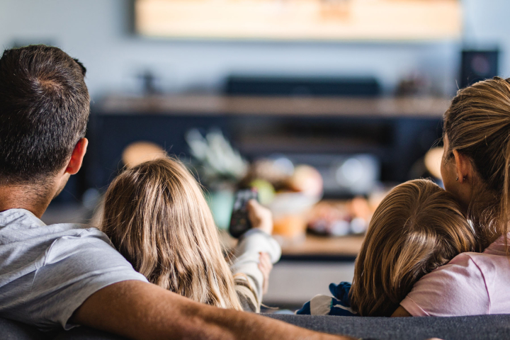 Familie gemütlich im Wohnzimmer, als Symbol für die Zuverlässigkeit des Stromnetzanschlusses von Groupe E