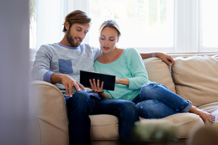 Ein Paar sitzt auf dem Sofa und analysiert die Energieverbrauchskurve des Haushalts