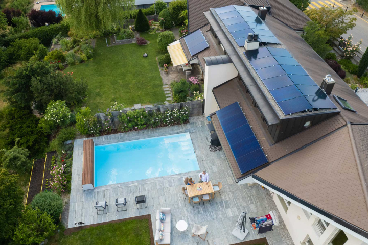 Vue aérienne d'une maison équipée de panneaux solaires, symbolisant l'engagement durable de Groupe E pour son produit électricité Vario destiné aux clients privés