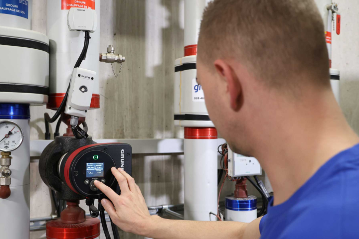 Un collaborateur de Groupe E effectue la maintenance d'un chauffage à distance chez un particulier