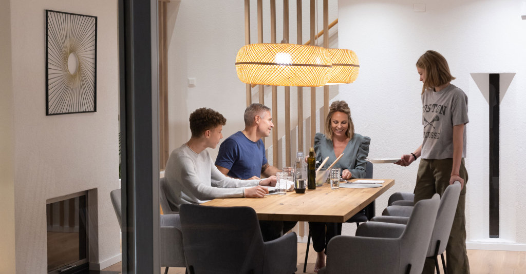 Une famille partage un repas dans une maison chauffée grâce à une solution de Groupe E