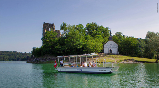 Un bateau électrique, équipé de panneaux solaires, navigant devant l'Île d'Ogoz