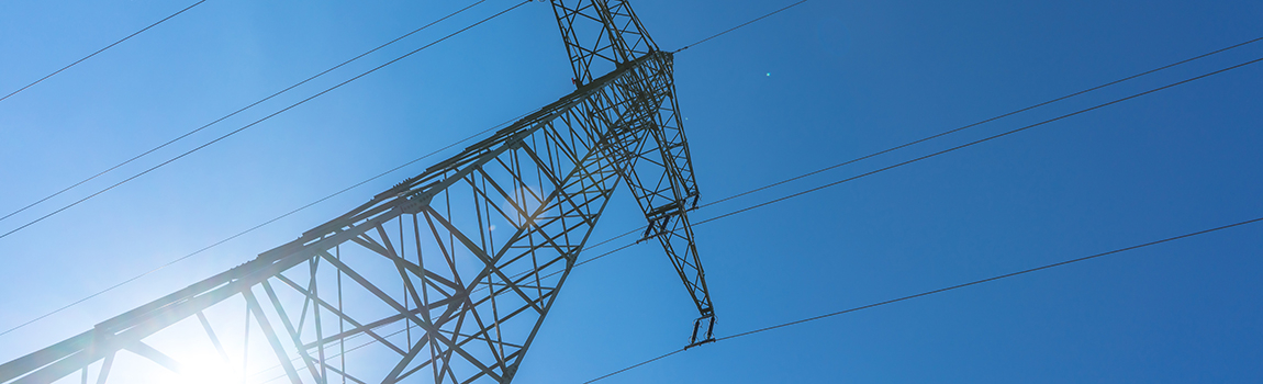Hochspannungsmast unter blauem Himmel mit Sonnenlicht, Energieinfrastruktur von Groupe E.