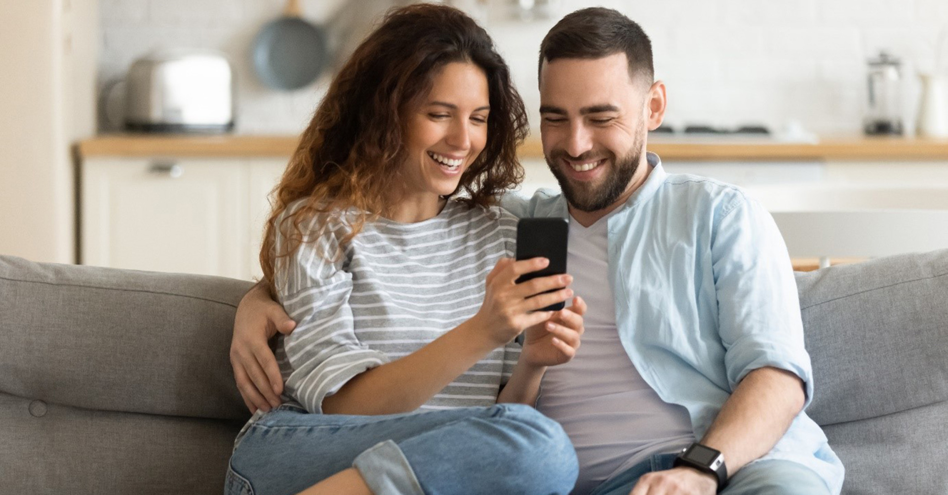 Un couple heureux qui consulte les prestations de Groupe E sur son smartphone